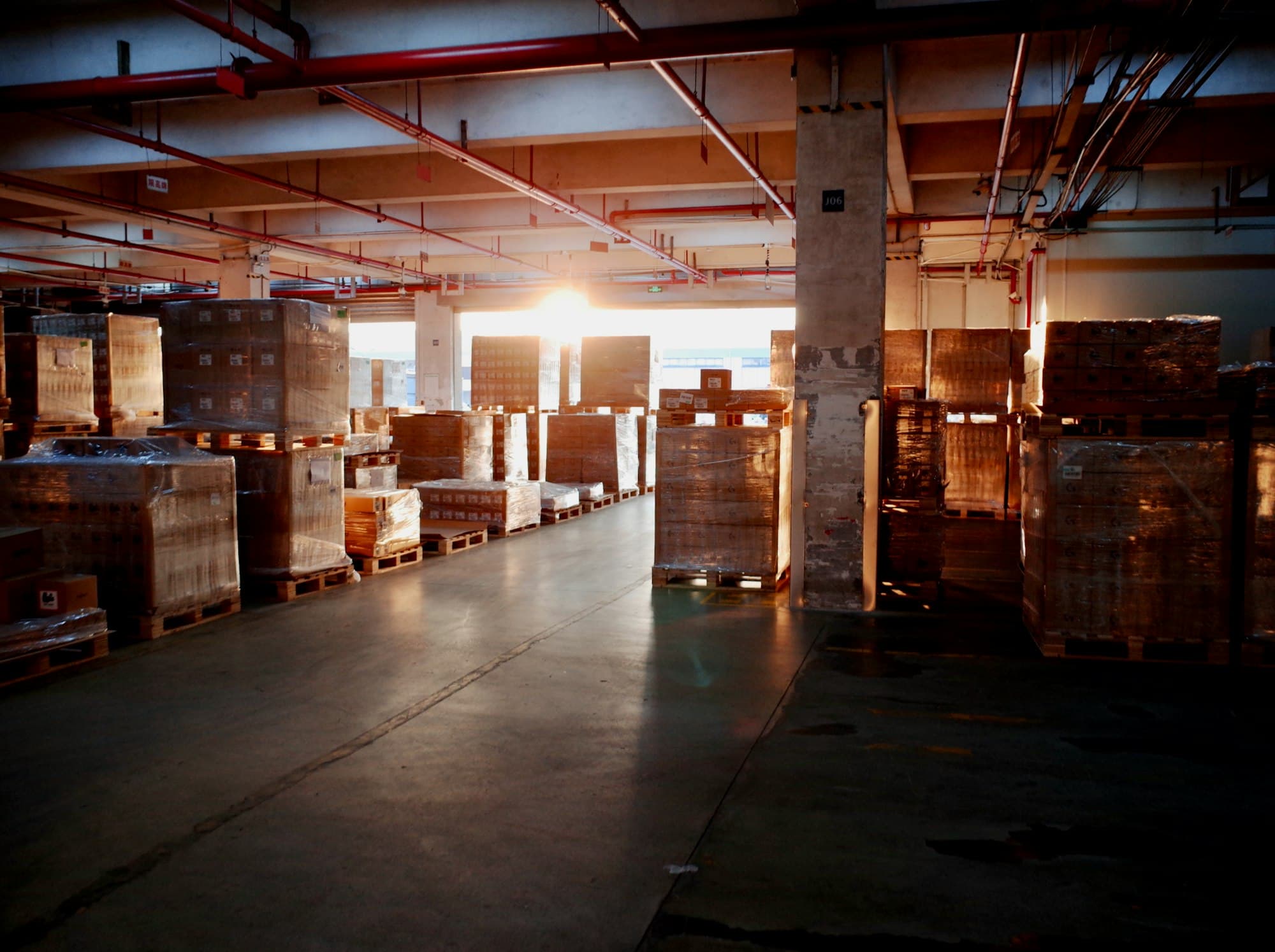A warehouse with stacked pallets in morning light